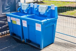 blue portable hand washing stations next to a fence